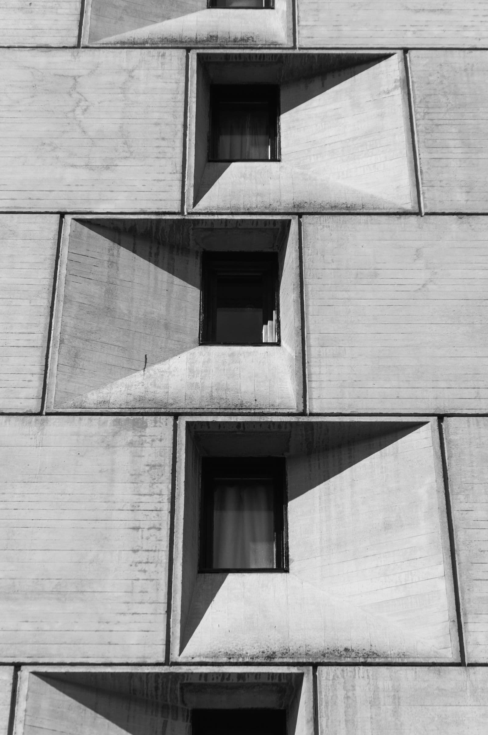 Concrete facade with deep window recesses casting slanted shadows