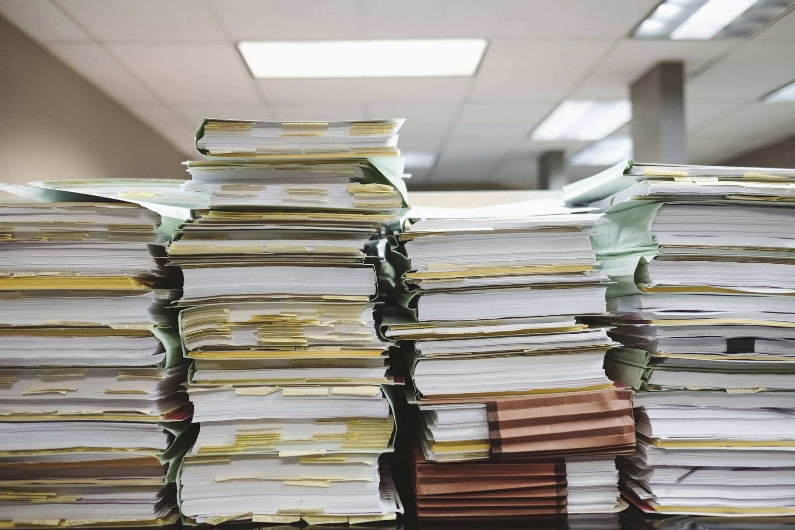 Stacks of documents and file folders on an office desk